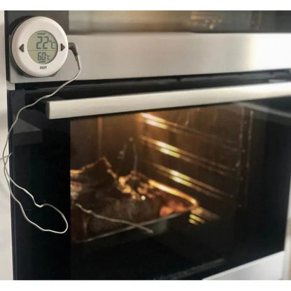 Le Thermomètre DOT pour four de Thermomètre.fr fixé sur le côté du four assure une cuisson facile en mesurant la température interne de la viande cuite à l'intérieur. L'affichage du thermomètre indique 22,2°C et 60,0°C, avec une alarme sonore pour une surveillance précise.