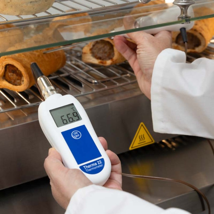 Une personne utilise un thermocouple Therma 22 ou thermistance de Thermomètre.fr pour vérifier la température interne des pâtisseries cuites sur une grille. Le thermomètre indique 66,9 degrés Celsius.