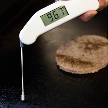 Un thermomètre numérique Thermapen® Surface de Thermomètre.fr affiche 96,7°F lorsqu'il plane au-dessus d'une galette en train de cuire sur la plaque chauffante.