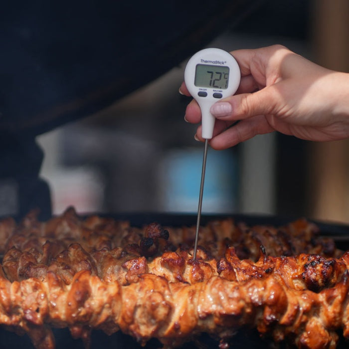 Une main tient un Thermomètres de poche ThermaStick de Thermomètre.fr, son écran LCD affichant clairement la température des brochettes de poulet grillées à 72,3°C.